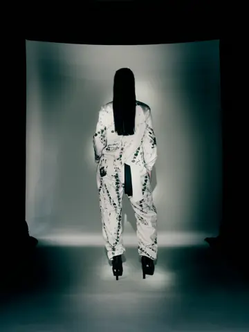 Model crouching beside a tyre in the printed jumpsuit