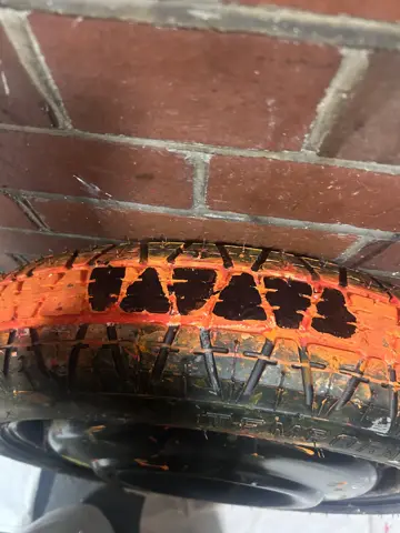 Tyre coated in orange fabric paint resting on fabric