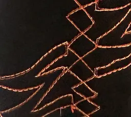 Close-up of metallic embroidery following tyre tracks