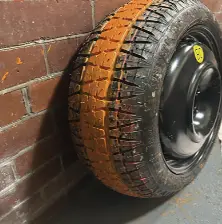 Tyre painted orange leaning against a brick wall