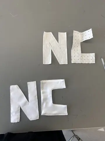 Hand-cut fabric letters N and C with visible stitching