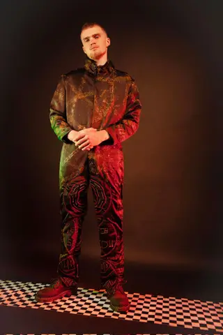 Model in embroidered jacket under red studio light